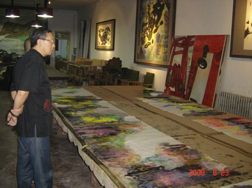 巨大的画桌，上面留下许多画家曾挥毫作画的色彩痕迹，墙上是已经完成的作品。